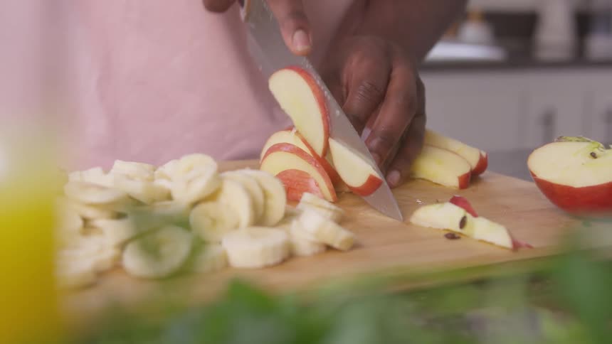 Person slices fruit while standing in the kitchen during the day