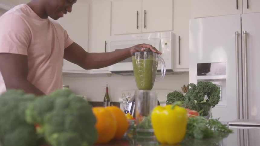 Blending a green smoothie with vegetables in a blender at home
