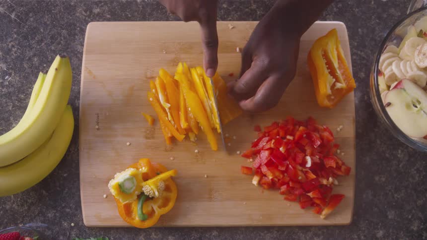 A person is slicing different types of vegetables in their kitchen