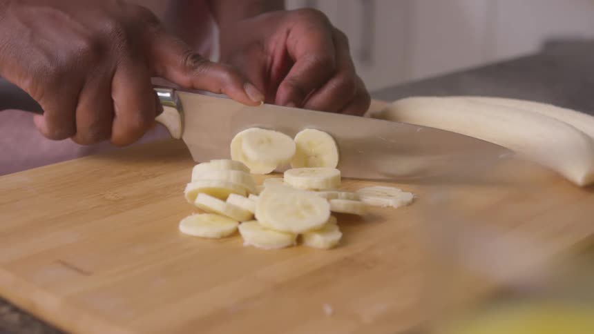 While standing in their kitchen a person is slicing a banana