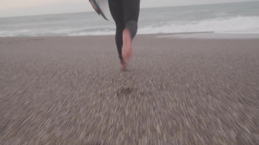 A surfer runs towards the ocean carrying their board