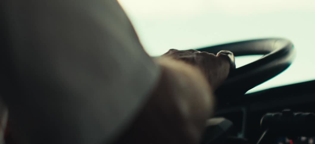 A persons hand wearing a ring grips a steering wheel