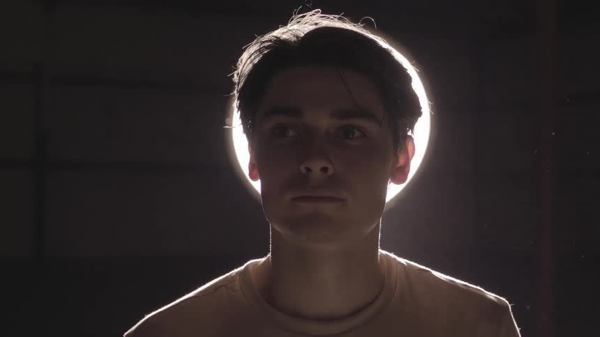 A male is standing in a room in front of a light fixture