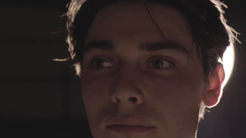 A male is standing in a room next to a bright light fixture