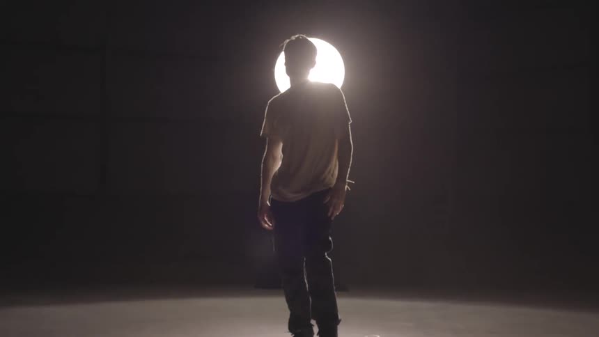 A male is standing on his skateboard during the night time
