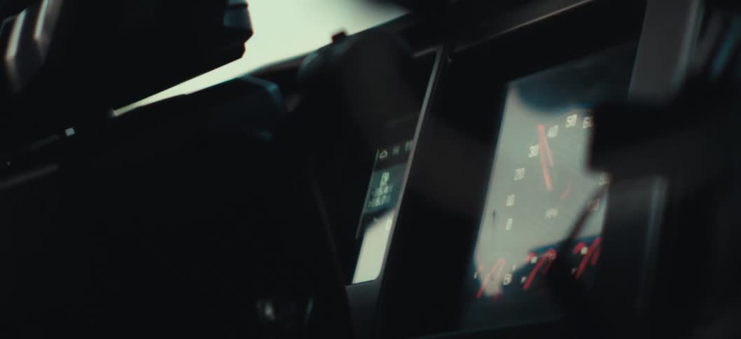 Closeup of a dashboard while the vehicle is steered past trees during the day