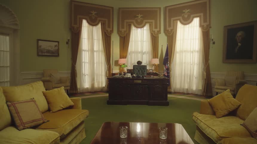 An elegant office features a large wooden desk three tall windows with ornate curtains two yellow sofas and various decorative elements