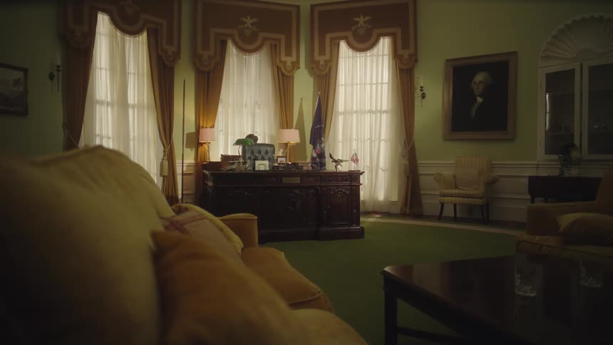 A formal office with a wooden desk tall windows a yellow sofa and a wall portrait exudes authority