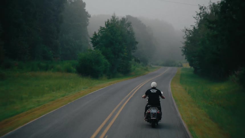 The road ahead of the motorcycle is covered in thick fog