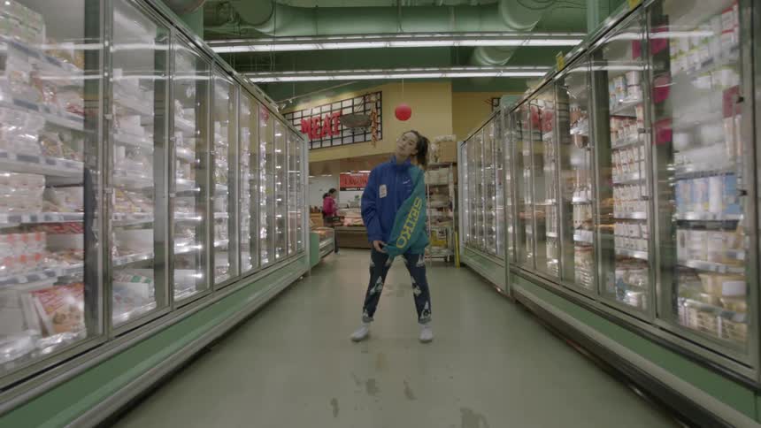Woman standing stationary in a grocery store in a frozen food aisle
