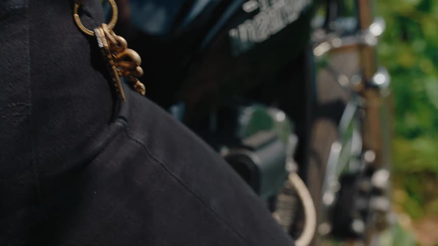 Male cyclist straddles a motorcycle on a summer day