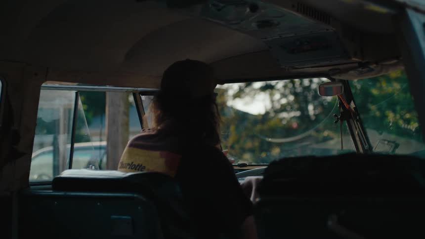 Surfer getting in his old vw bus then flipping open the safari front windows