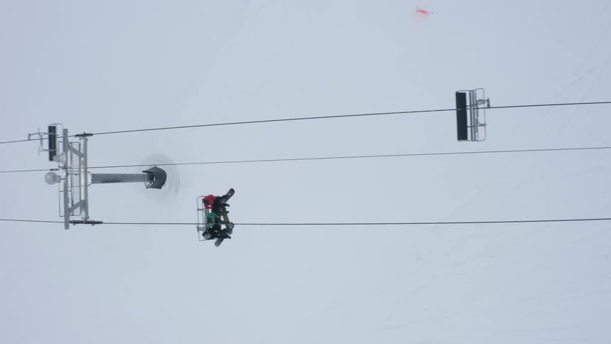 People with disk and air equipment going up a cable car on a snowy mountain