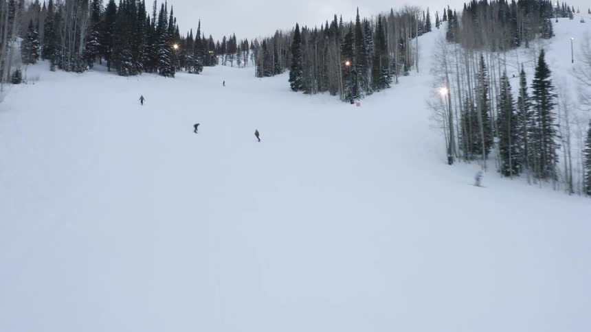 People are skiing and snowboarding fast down the slope