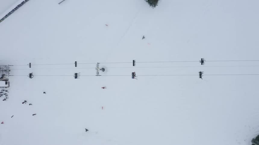 Aerial view of people climbing a snowy mountain by cable car and others skiing