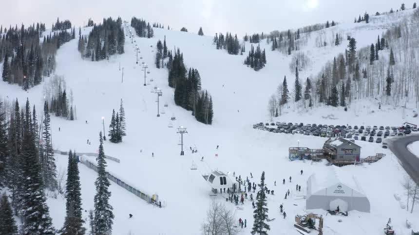 Aerial panorama of a snowy mountain park with ski lifts and people skiing
