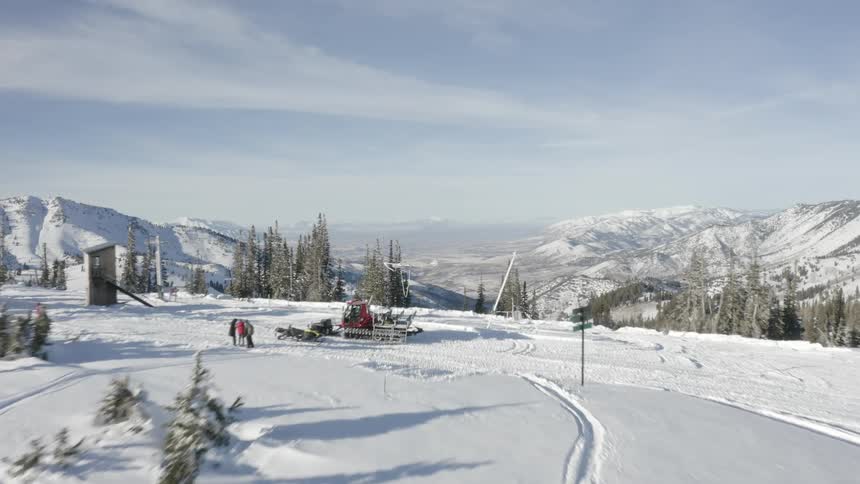 Aerial view of some people with a truck on the peak of a snowy mountain