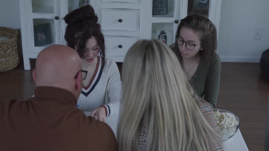 A family play a game at home with dice