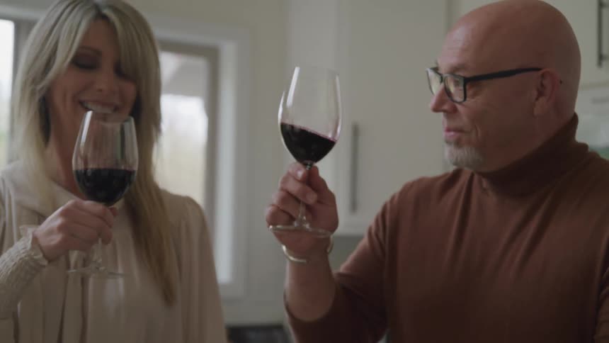 A man and woman toast their wine glasses and drink