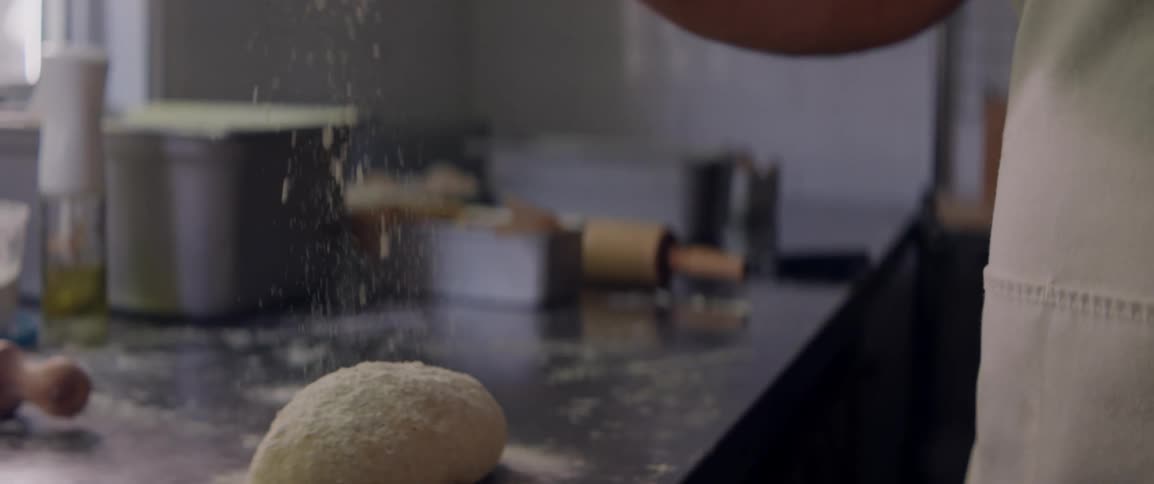 A man sprinkles flour on some dough