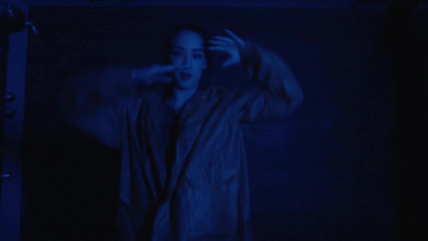 Woman dancing in the dark with blue light shining on her