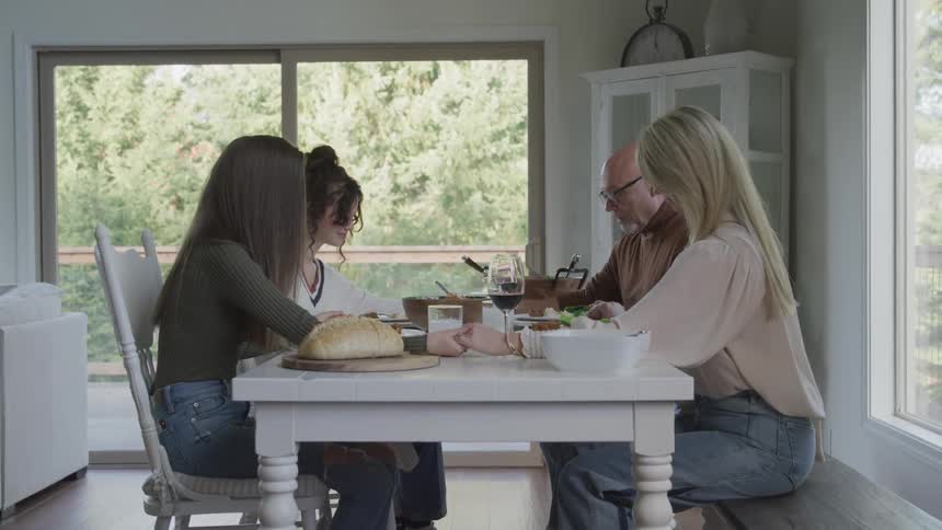 A family bow their heads and pray before eating