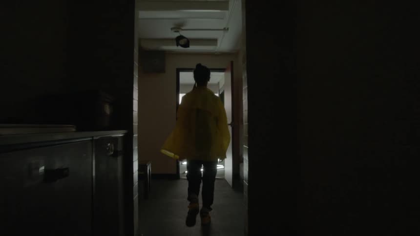 Woman walks down a dark hallway out the door