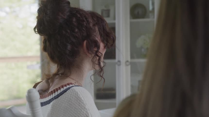 A girl smiles while listening to people at the dining table