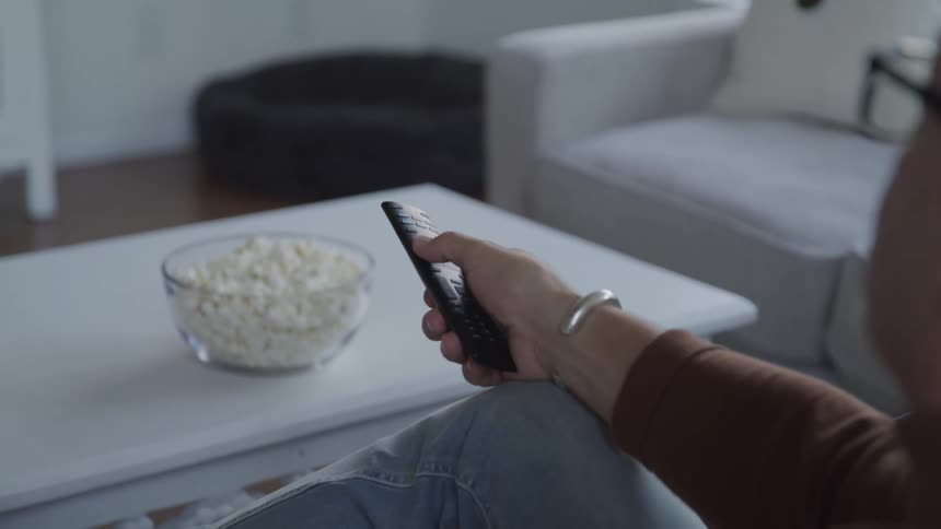 Mans hand interacting with a television remote control