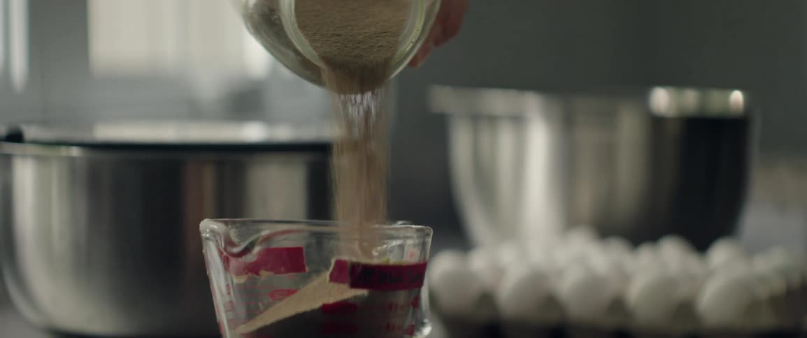 Hand pouring yeast into a glass measuring cup
