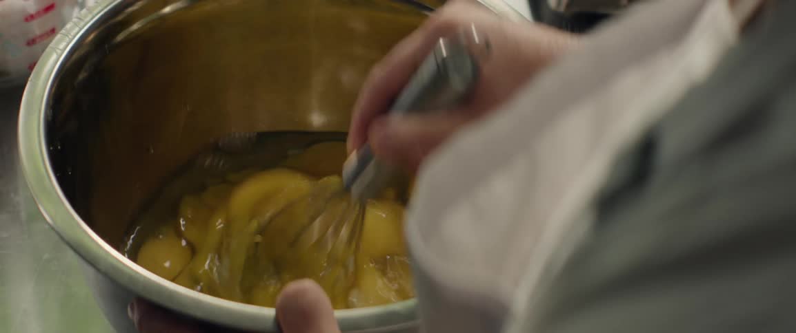 A cook is mixing a bowl full of many eggs