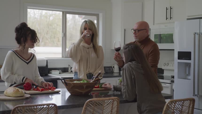 Family in the kitchen with parents toasting and drinking wine