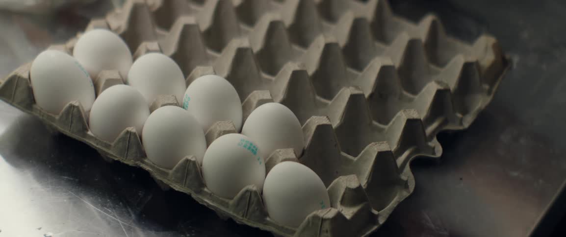 A person cracks an egg on a counter