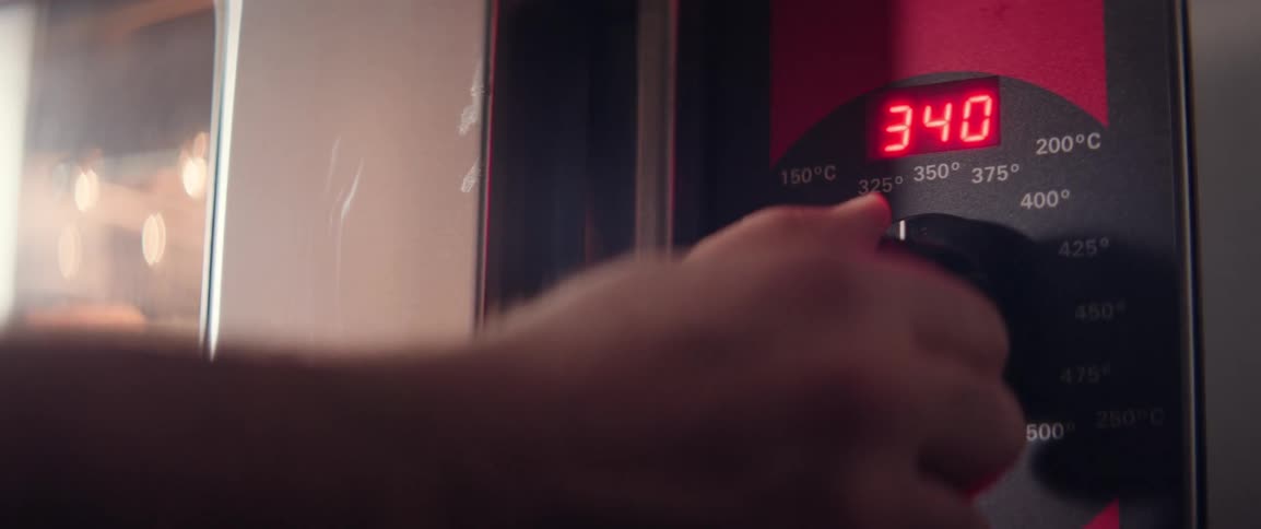 A person is setting the temperature on a kitchen oven