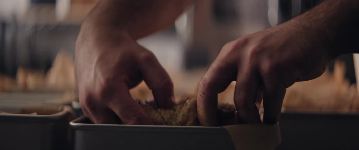 A person is placing dough in a pan so they can cook it