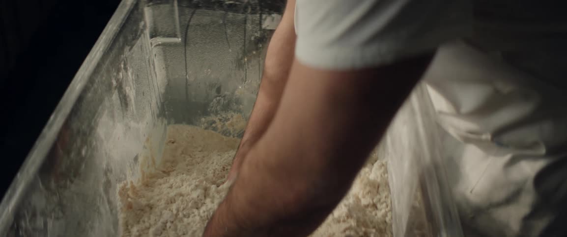 A man mixes dough in a large container