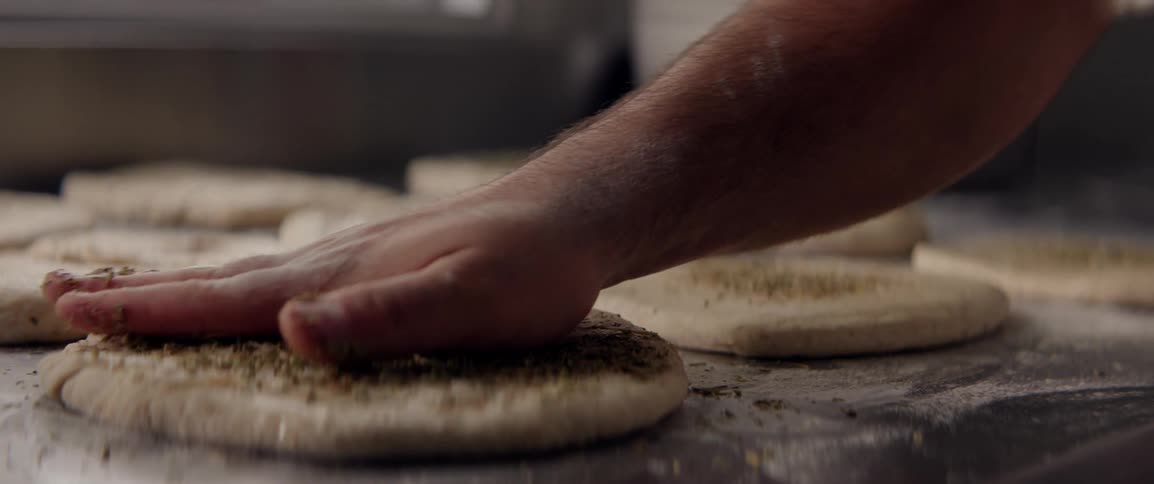 A person is rubbing seasoning into fresh dough