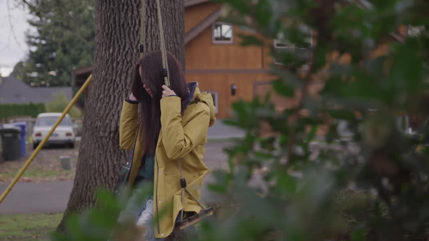 A girl is on a swing located at a suburban park