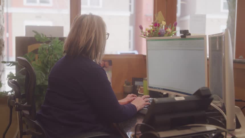 Woman sitting working in front of a computer typing on the keyboard
