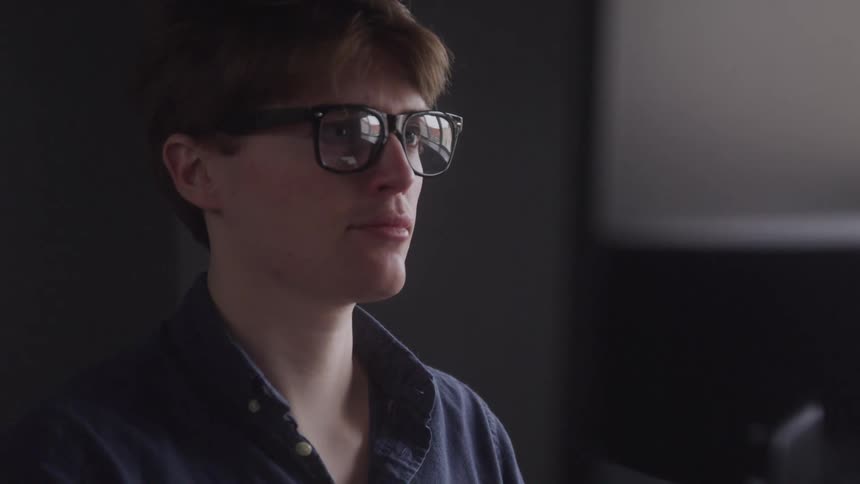 Man wearing glasses in an indoor space with a focused expression