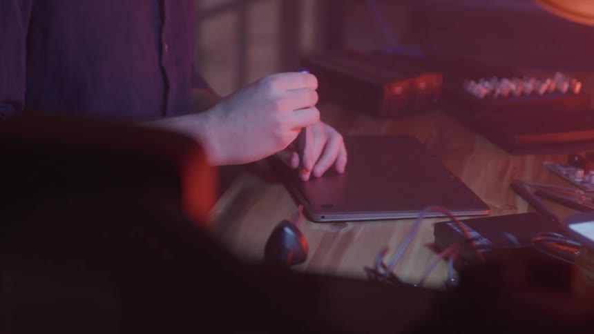Pair of hands disassembling a laptop by removing the screw from the back