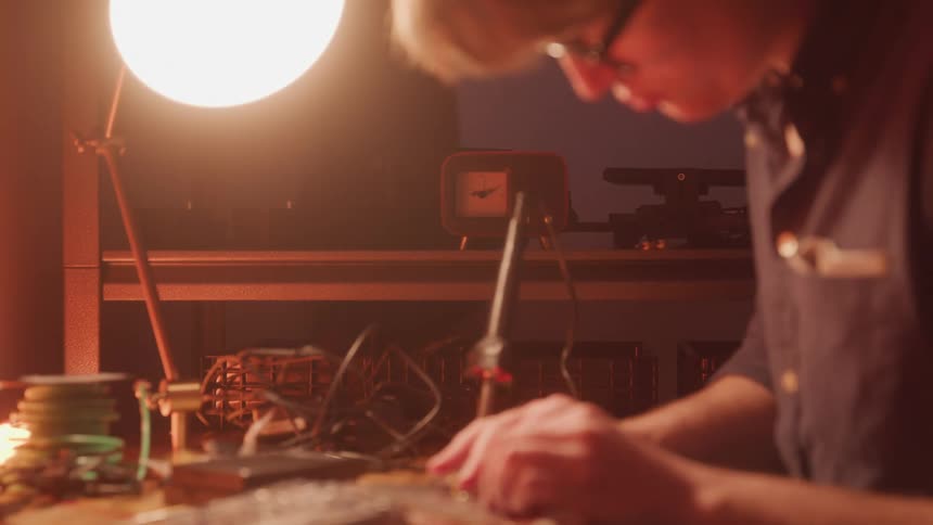 Man sitting at a table with a lamp working