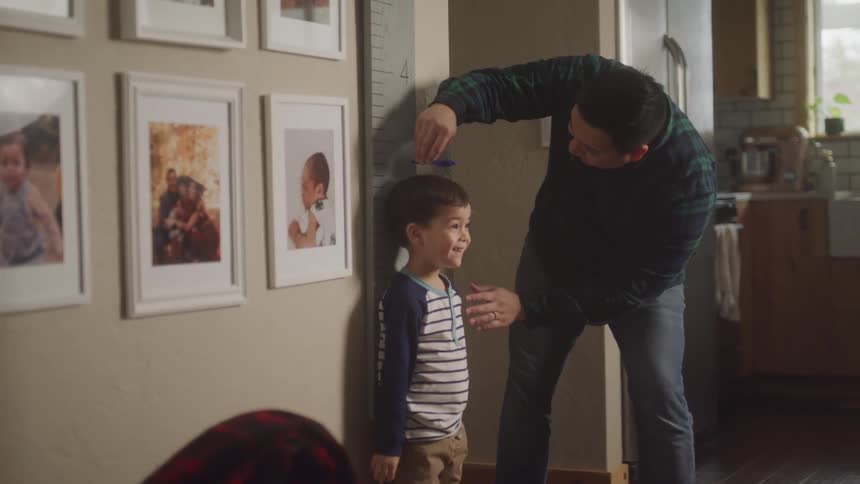 A footage of a father measuring the height of his son
