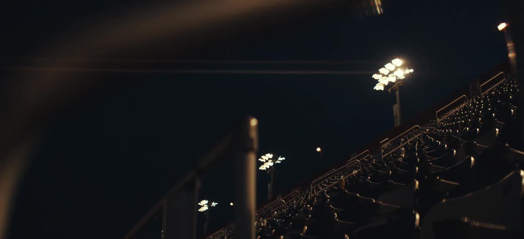 Empty stadium stands seen at night with floodlights on