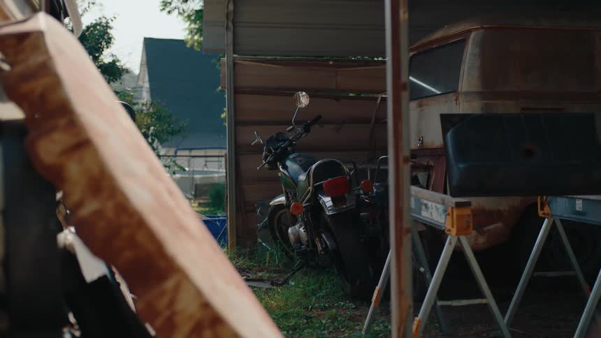 Motorcycle parked next to a rusty kombi in a garage