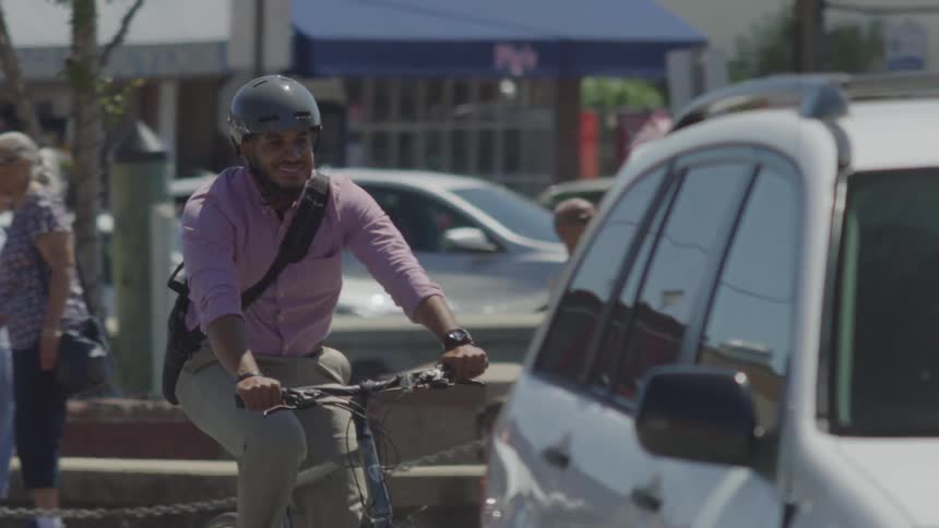 A man rides his bike behind the cars