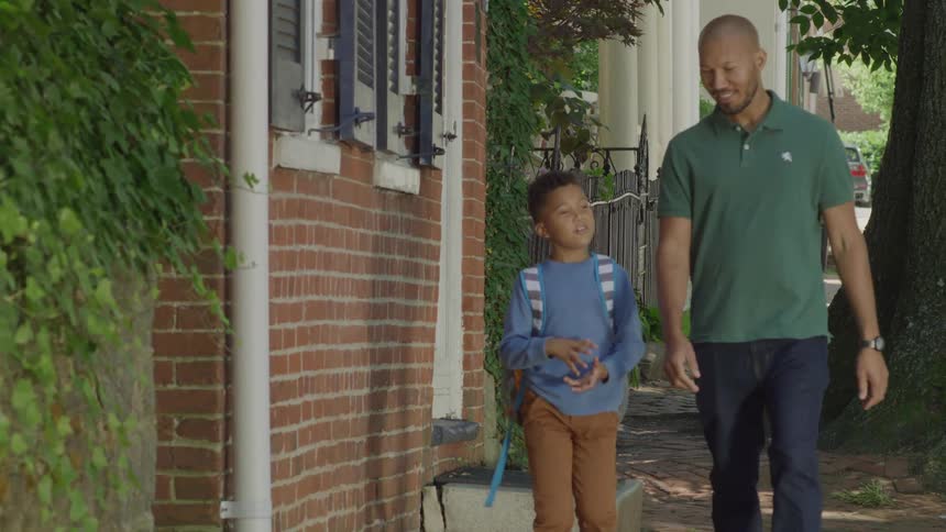 A father and son walk on the sidewalk together