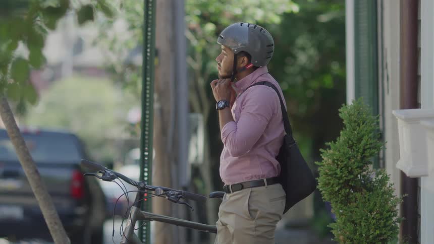 Man leaving home putting on his helmet and taking his bike