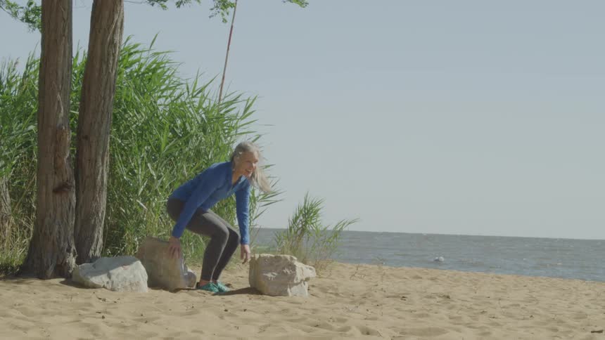 A woman walks on the beach and sits by a tree
