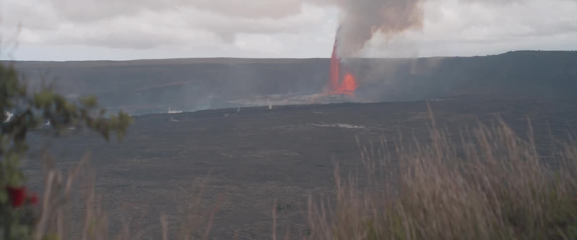 A volcanic eruption produces a thick plume of smoke on a cloudy day
